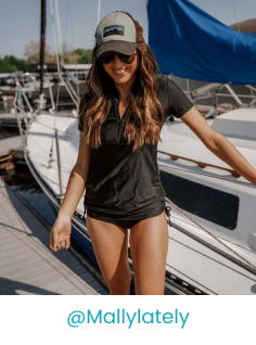 Happy lady wearing black swimwear with yacht background