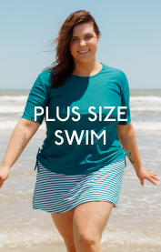 Woman wearing solid dark jade swim top with striped skort by the beach