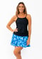 Girl wearing black spaghetti strap swim top with blue tie flowy swim skort in solid white background