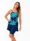 Woman wearing navy floral spaghetti strap swim top  with navy swim skort in solid white background