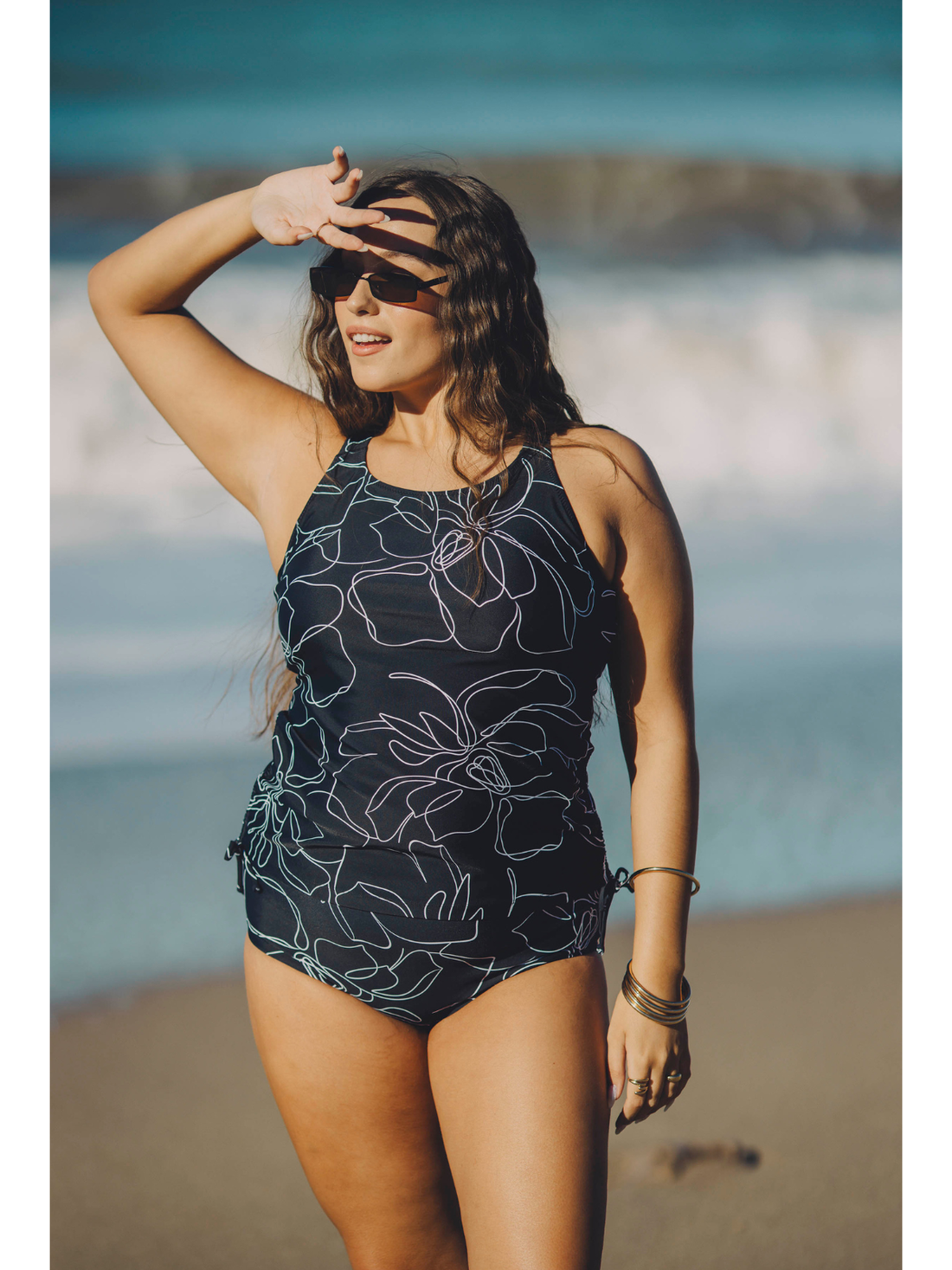 Woman wearing Maya Tankini Swim Top With Removable Cups | Plus Size in a floral print at the beach, showcasing size-inclusive, modest swimwear with a supportive and comfortable fit. Swimwear designed for every body.