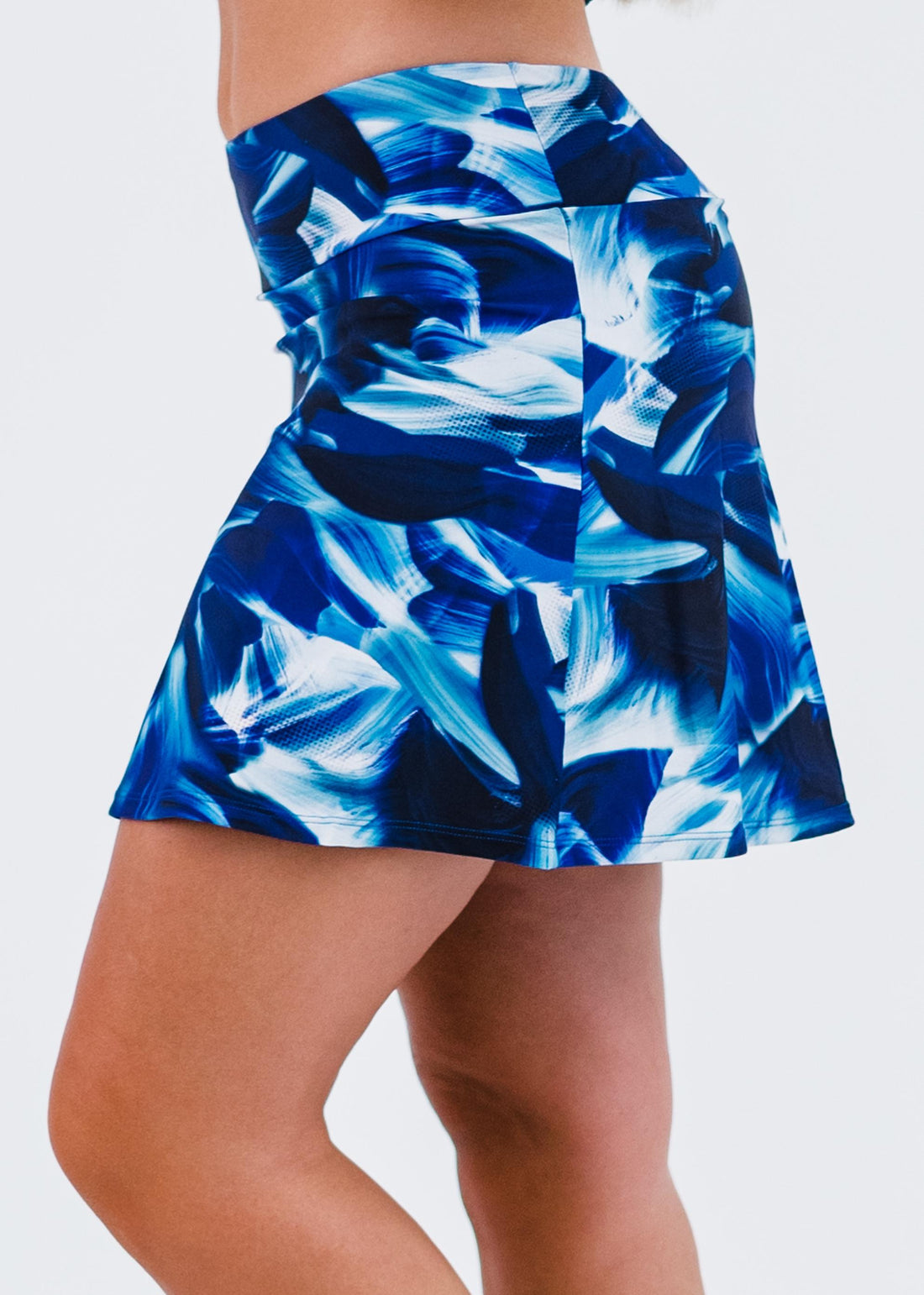 Blue abstract patterned skirt worn by a person on a white background