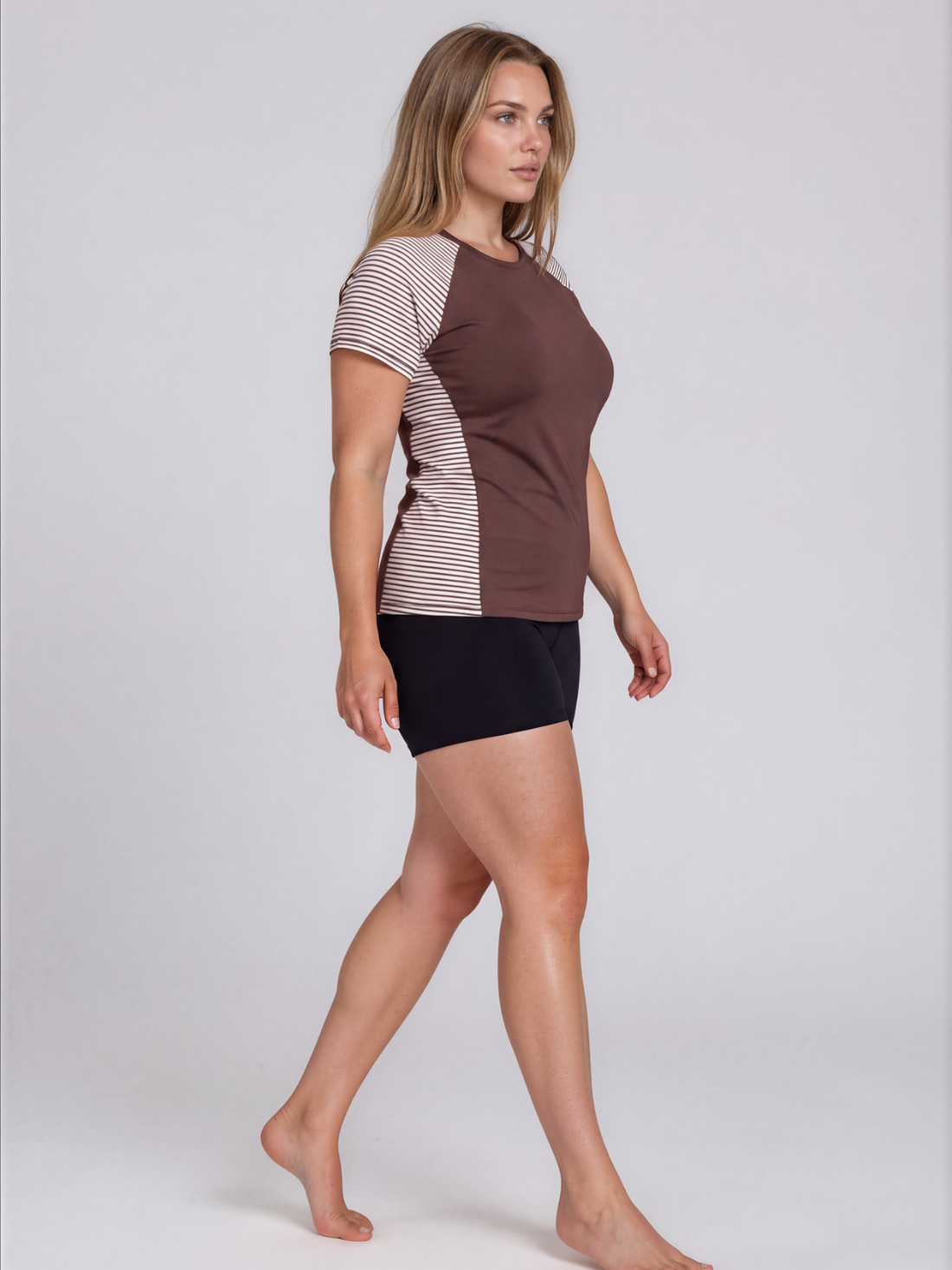Model wearing Loose Fit Adele Swim Top with striped short sleeves and side panels over black swim shorts showcasing size inclusive supportive swimwear for every body