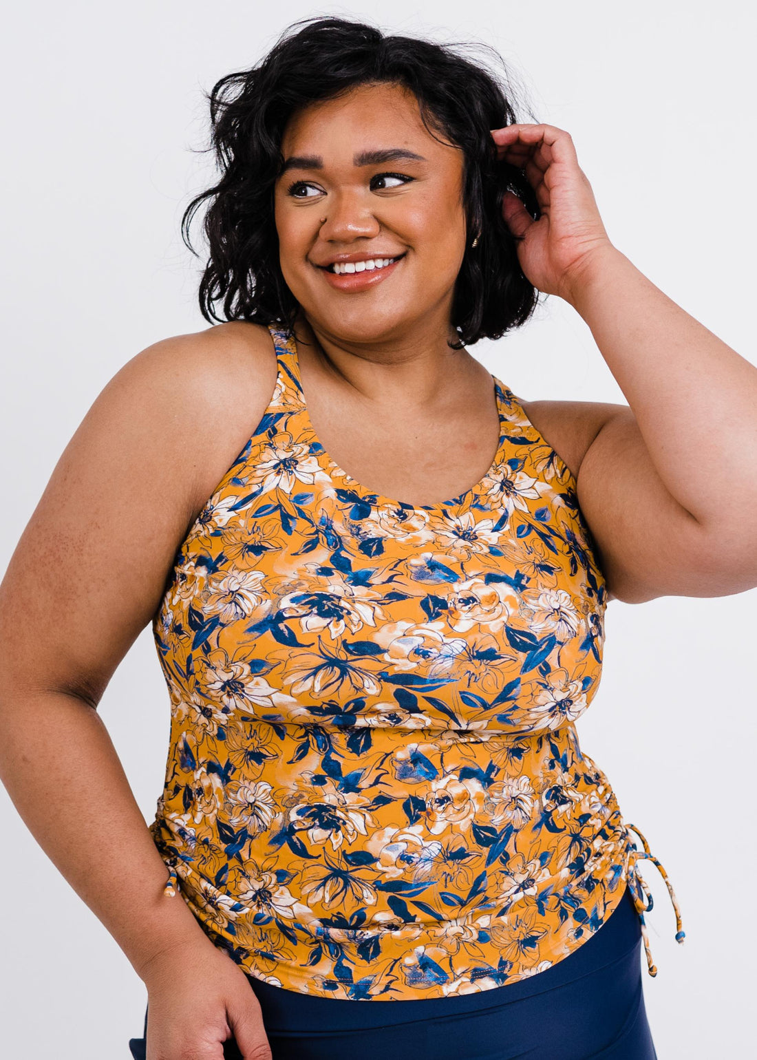 Woman wearing a yellow floral tank top against a white background