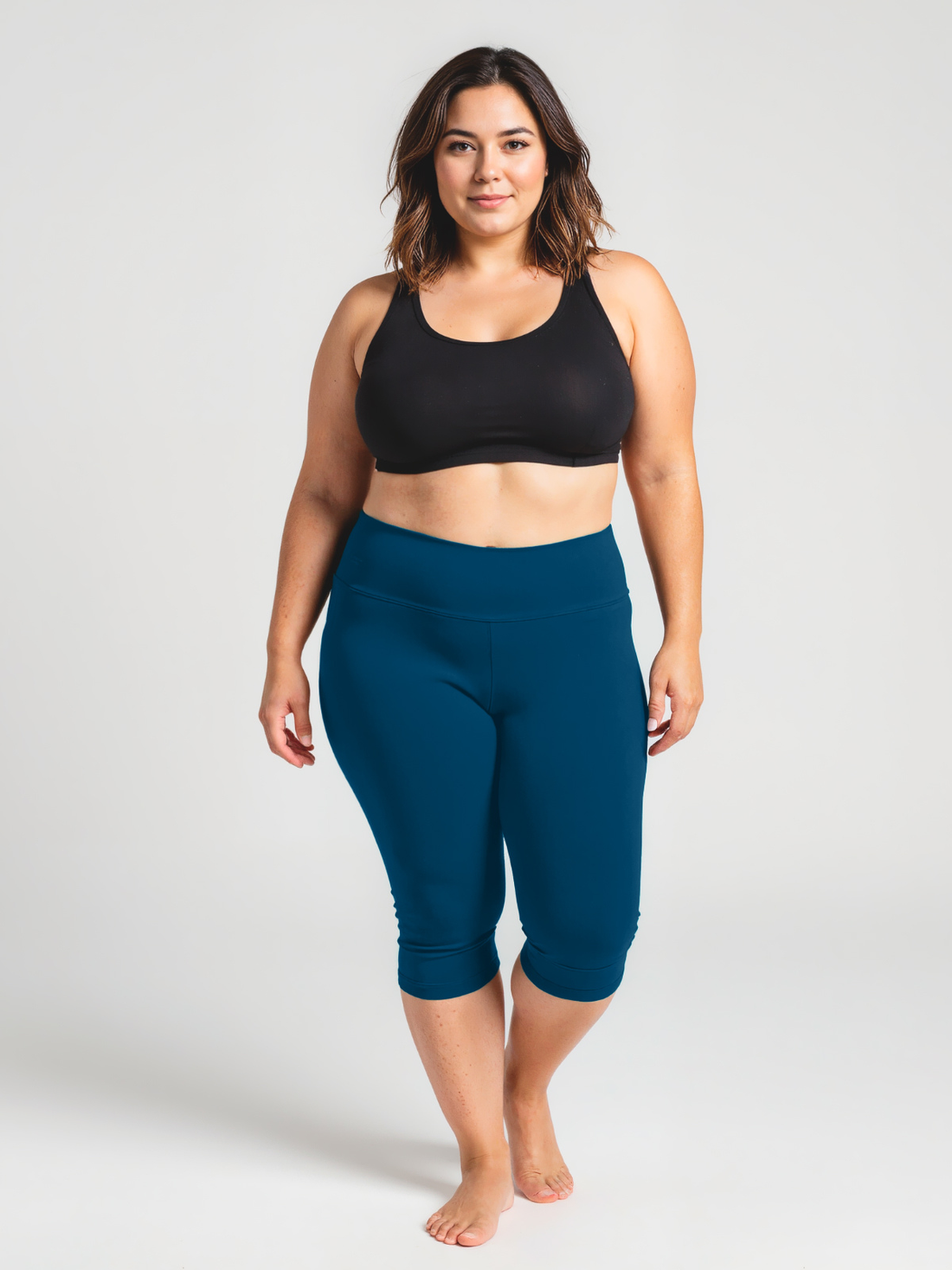 A confident plus size woman wearing Capri Swim Leggings | Plus Size in a deep blue color paired with a black supportive swim top, showcasing size-inclusive, modest swimwear designed for every body.